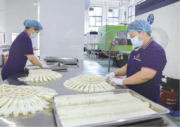 广宁美好生活塑料制品有限公司工人在制作蛋糕餐具，未来将采用竹塑料作为原料。